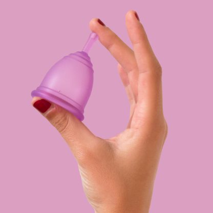 Paarse Ruby Cup menstruatiecup tussen duim en middelvinger vastgehouden